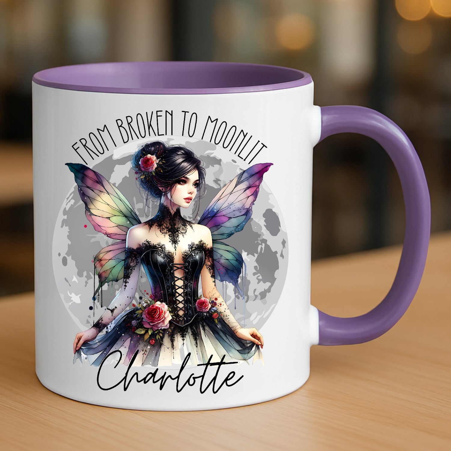 Mug with gothic fairy and moon design and text 'From Broken to Moonlit' on a wooden surface. Personalised with any name.