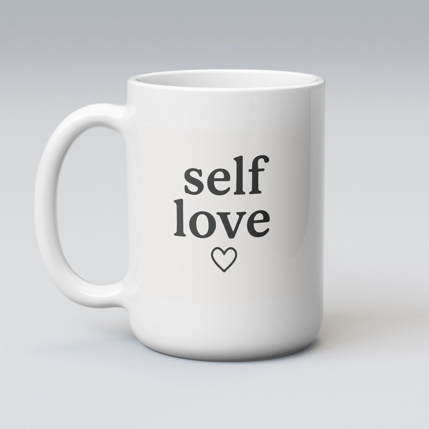 Large white 15oz ceramic mug featuring the phrase "self love" with a heart underneath, printed in sleek black lettering. Perfect for big brews and bold affirmations.