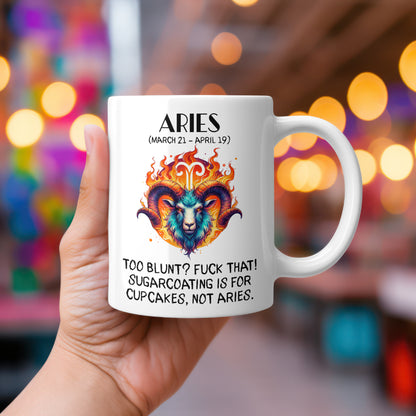 A white 11oz coffee mug featuring a bold Aries-themed design. The artwork showcases a fierce ram’s head engulfed in flames, with the Aries zodiac symbol glowing above it. The fiery colour palette reflects Aries' passionate and direct personality. Below, the sassy text reads: "Too blunt? Fuck that! Sugarcoating is for cupcakes, not Aries." A cheeky, rude astrology gift for Aries star sign lovers.