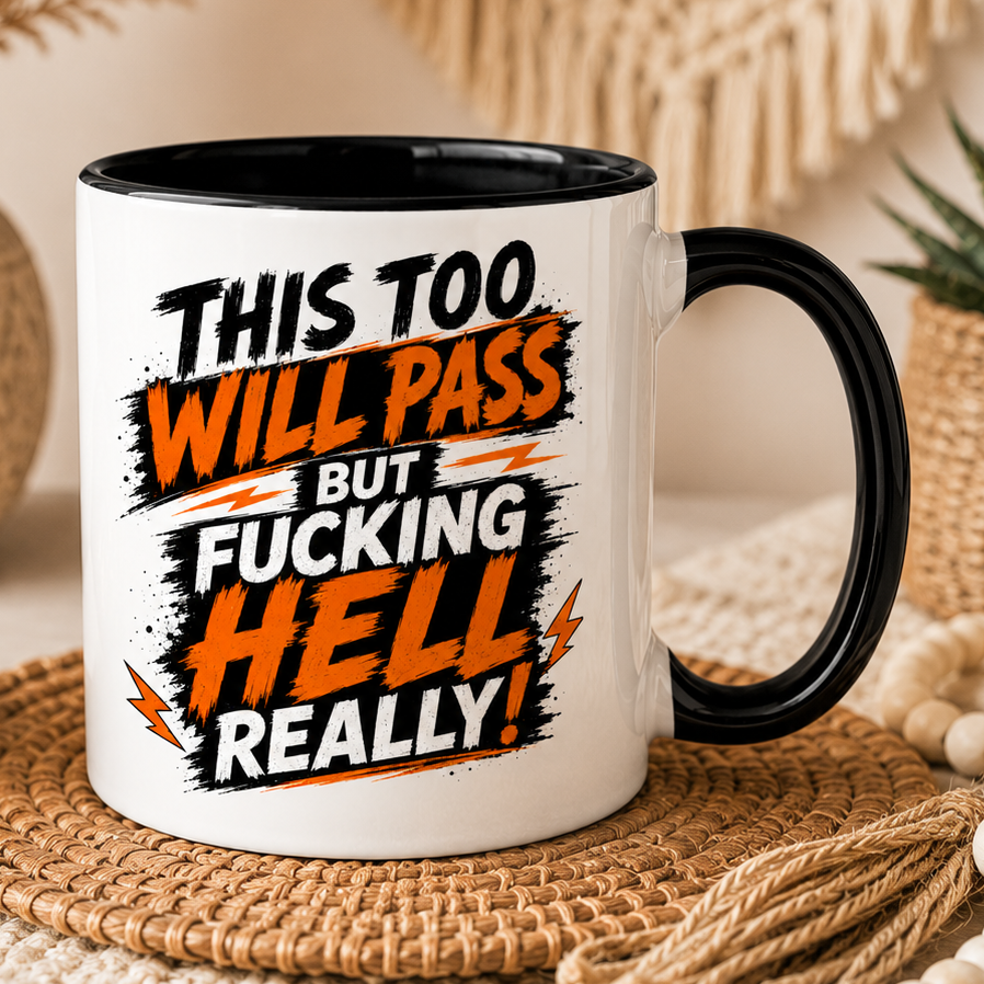 White ceramic funny quote mug featuring the phrase “This Too Will Pass But Fucking Hell Really” in bold black and orange typography. Displayed in a cosy boho-style setting with neutral décor and soft lighting. Available in multiple inner and handle colour options including black, pink, blue, red and yellow.