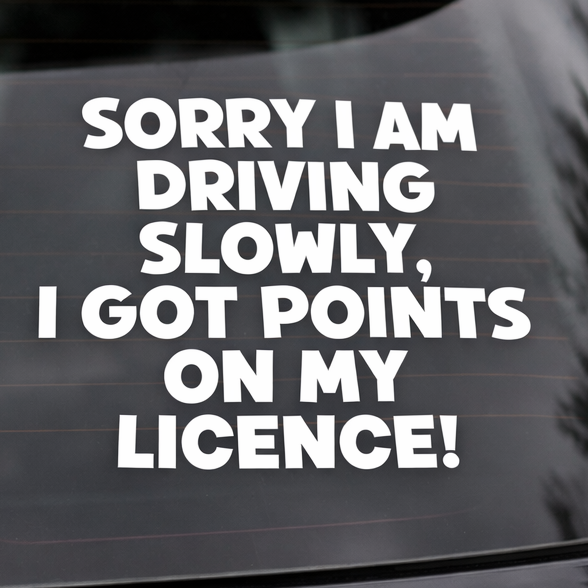 Car window with a humorous decal about driving slowly due to license points. Vinyl sticker says - Sorry I am driving slowly I got points on my licence!