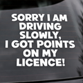 Car window with a humorous decal about driving slowly due to license points. Vinyl sticker says - Sorry I am driving slowly I got points on my licence!