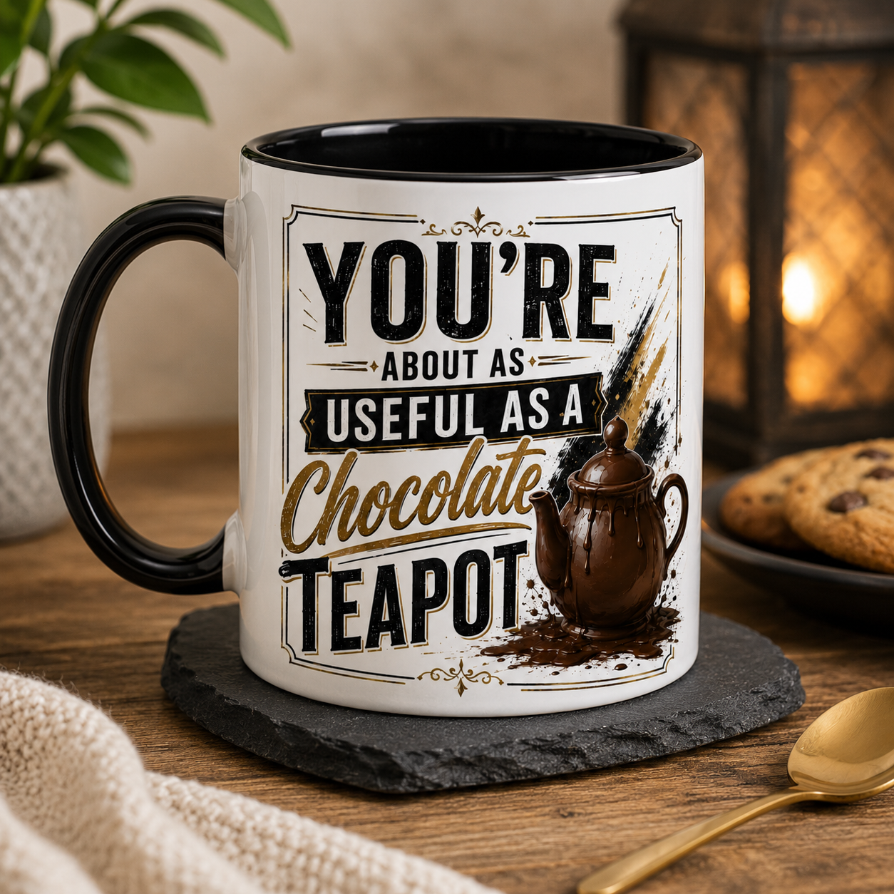 Mug with humorous text design saying - You're about as useful as a chocolate teapot on a wooden table with a plant and cookies in the background