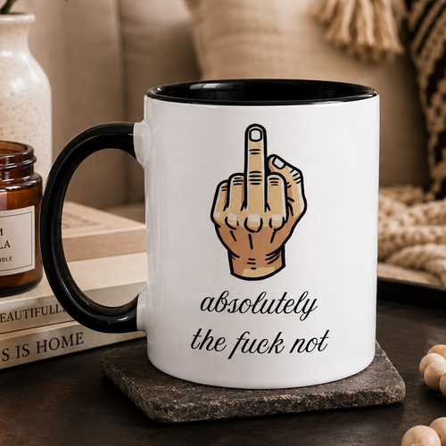 Mug with middle finger gesture and text saying absolutely the fuck not funny coffee mug on a table with a cozy background.