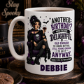 White mug with a witch design and text, surrounded by Halloween-themed decor.
