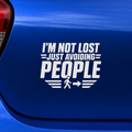 White text decal on a blue car reading 'I'm not lost just avoiding people' with a small graphic of a person walking away.